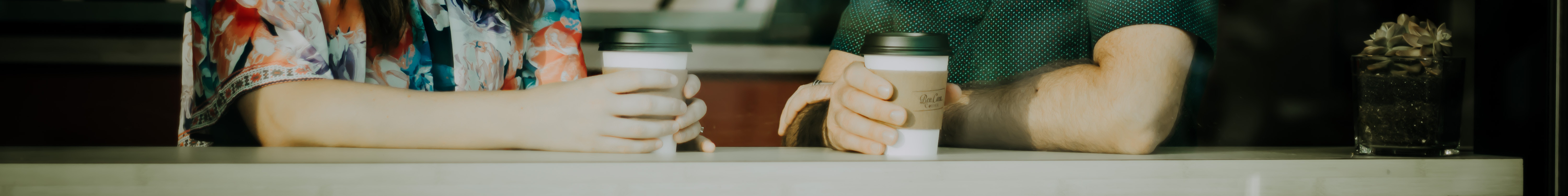 Banner image showing two people talking whilst drinking coffee.